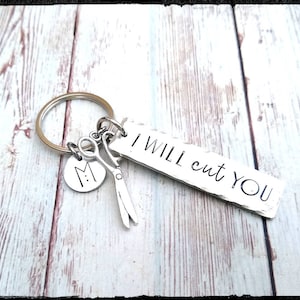 May include: Silver keychain with a charm that says "I will cut you" and a small charm with the letter "M" and a pair of scissors.