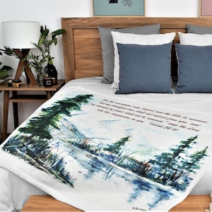 May include: White throw blanket with a watercolor painting of a lake and trees. The blanket has a quote from the Bible, "For the mountains may depart and the hills be removed; but my steadfast love shall not depart from you, and my covenant of peace shall not be removed," says the Lord.  Psalm 89:10"