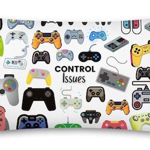 Peut inclure: Coussin rectangulaire avec un fond blanc orné d'illustrations colorées de manettes de jeux vidéo. Le texte "CONTROL Issues" est au centre. Les manettes sont de différentes couleurs, dont le jaune, l'orange, le bleu et le gris.