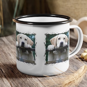 May include: White enamel mug with a black rim featuring a photo of a golden retriever puppy peeking through a fence. The puppy is looking at the camera with a curious expression. The photo is surrounded by a decorative floral border.