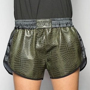 Puede incluir: Shorts deportivos verdes y negros con estampado de cocodrilo y una cintura negra con la palabra "ZAT" en blanco.