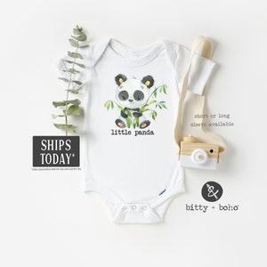 May include: White baby onesie with a black and white panda bear illustration holding bamboo. The text "little panda" is printed below the panda. The onesie is available in short or long sleeves.