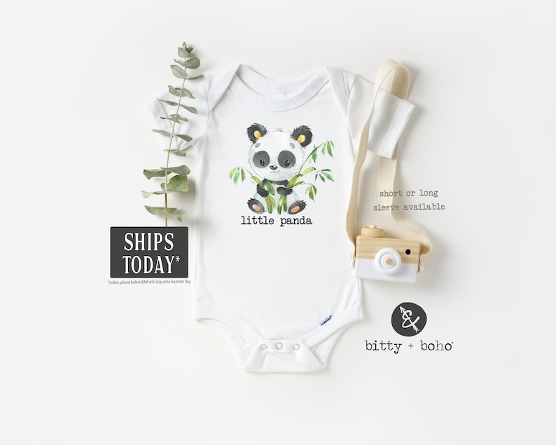 May include: White baby onesie with a black and white panda bear illustration holding bamboo. The text "little panda" is printed below the panda. The onesie is available in short or long sleeves.