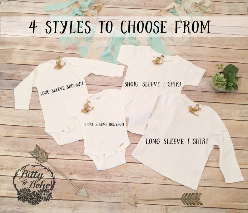 Puede incluir: Cuatro prendas de vestir blancas para beb&eacute;s se muestran sobre una superficie de madera: un body de manga larga, un body de manga corta, una camiseta de manga corta y una camiseta de manga larga. El texto "4 STYLES TO CHOOSE FROM" est&aacute; en la parte superior.