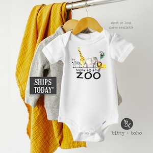 May include: White baby onesie with a graphic of a zebra, giraffe, elephant, and lion with the text "New to the Zoo".