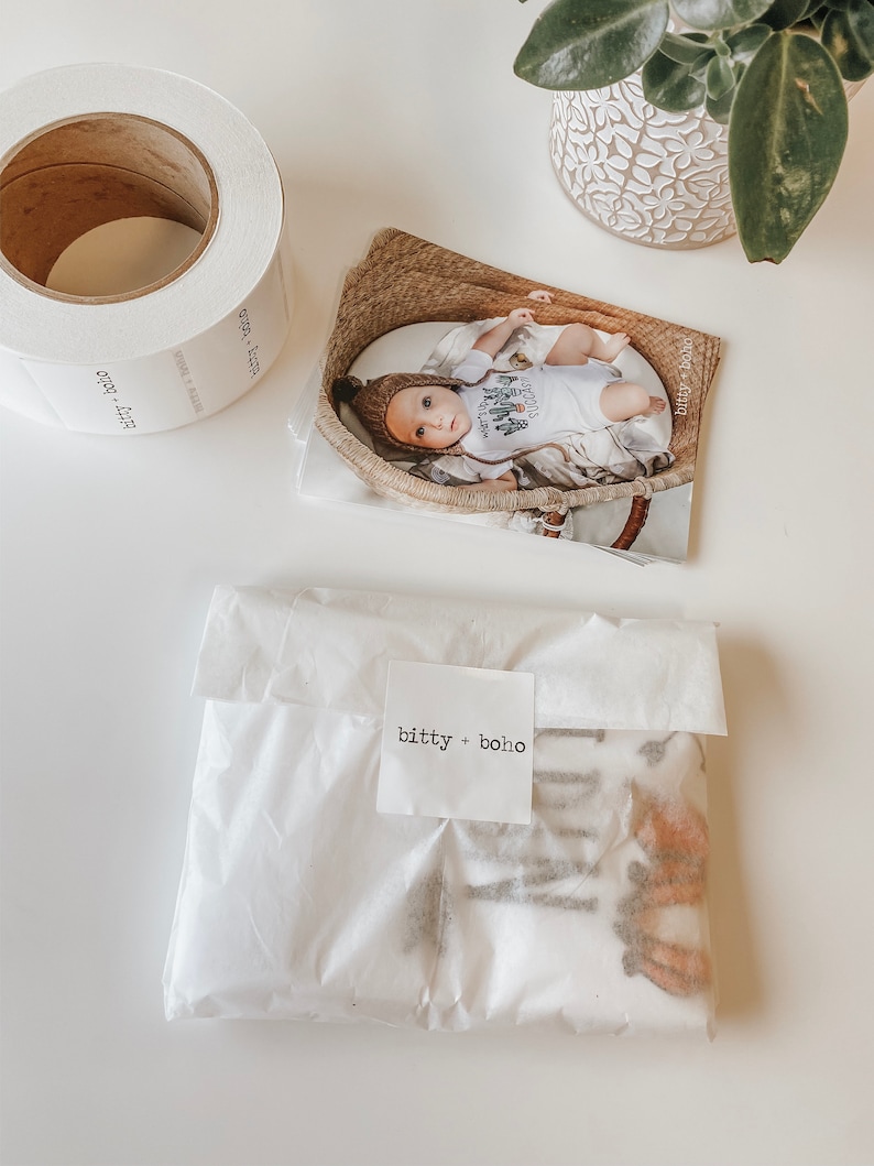 May include: A white, tissue paper-wrapped package with a small white label that reads "bitty + boho". The package is sitting on a white surface.