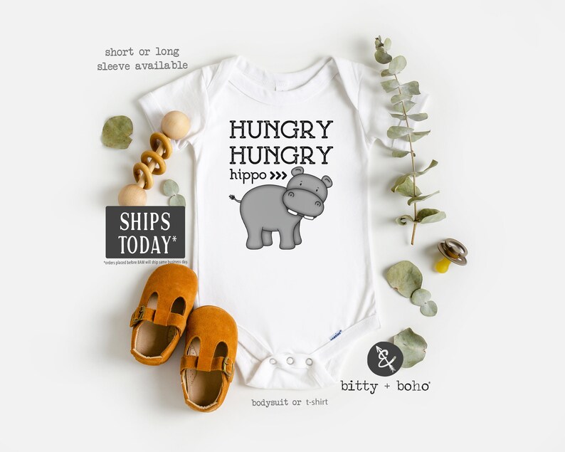 May include: White baby onesie with a gray hippopotamus illustration and the text "HUNGRY HUNGRY hippo >>>".
