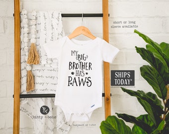 May include: White baby onesie with black text that reads "My Big Brother Has Paws".