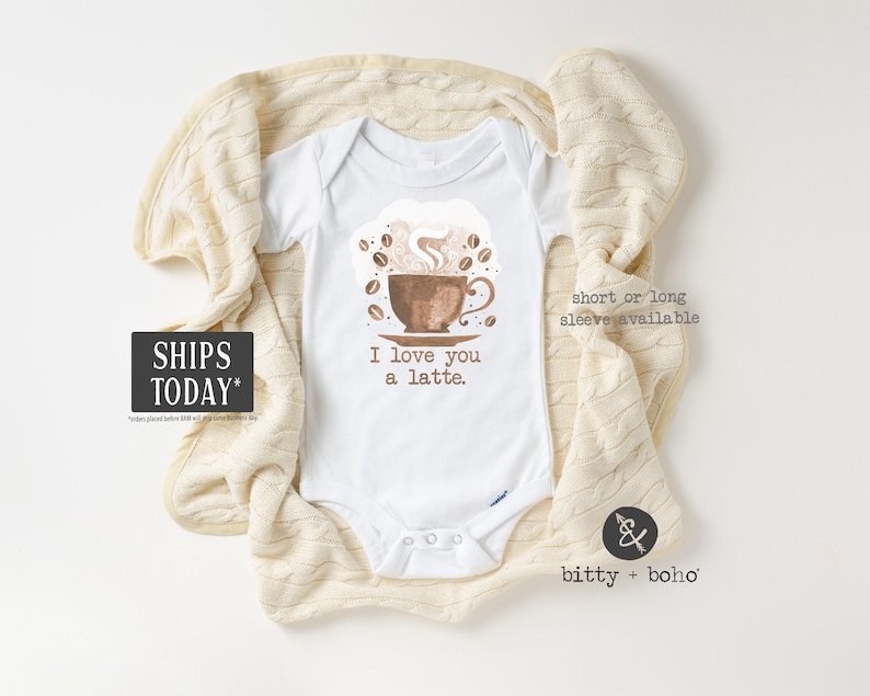 May include: White baby onesie with a brown coffee cup and steam, surrounded by brown coffee beans. The text "I love you a latte." is printed on the onesie.