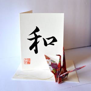 Biglietto di Natale con calligrafia giapponese Shodo spazzolata a mano e ornamento con gru di carta: pace, amore, felicità, gioia e felicità
