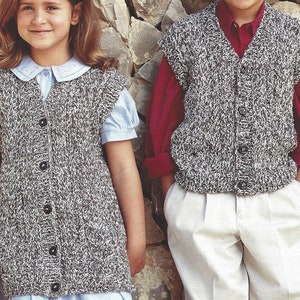 Puede incluir: Dos niños con chalecos de punto gris y blanco con botones. El chaleco tiene cuello en V y es sin mangas. Los niños están de pie frente a una pared de piedra.