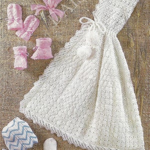 May include: A set of crocheted baby clothes, including a white dress, a pink hat, pink booties, and blue booties with a chevron pattern.