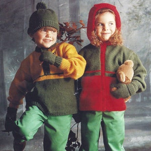 Puede incluir: Dos niños con ropa de invierno de punto. El niño lleva un suéter verde y amarillo, pantalones verdes y un gorro de punto verde. La niña lleva una chaqueta roja y verde con capucha roja, pantalones verdes y guantes de punto verde. Ella lleva un oso de peluche marrón.