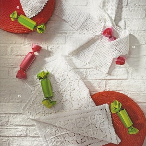 May include: Three white crocheted items: a hat, a jacket, and a blanket. The items are displayed on red and white backgrounds with green and pink accents.