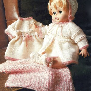May include: A knitted doll outfit set in white and pink. The set includes a dress, a cardigan, a hat, and booties. The outfit is perfect for a doll that is about 12 inches tall.