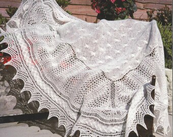 May include: A white crocheted shawl with a delicate lace pattern. The shawl is draped over a wooden chair and has a scalloped edge.