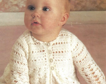 May include: A white crocheted baby cardigan with button closures. The cardigan has a delicate openwork pattern and is perfect for a special occasion.