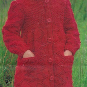 May include: A red knitted coat with a matching red knitted beret. The coat has a button closure and pockets. The girl is wearing white socks.