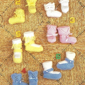 May include: A collection of ten knitted baby booties in various colors, including yellow, white, pink, and blue. The booties are displayed on a woven straw mat.