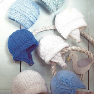 May include: Seven knitted baby hats in various colours, including white, blue, and light blue, are displayed against a light blue wooden background. The hats are arranged in a semi-circle, with some hanging from a rope. The hats have different styles, including some with ear flaps. The text "Includes Premature Sizes" is visible in the top left corner of the image.