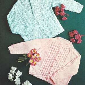 Può includere: Due cardigan di maglia, uno azzurro chiaro e uno rosa, con chiusura a bottoni. Entrambi i cardigan presentano un motivo a maglia testurizzato.