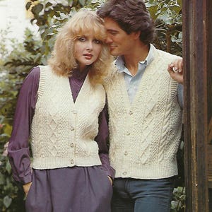 Może przedstawiać: Dwie osoby w kremowych dzianinowych kamizelkach z guzikami. Kamizelki mają wzór w romby. Kobieta ma na sobie fioletową koszulę i czarną spódnicę. Mężczyzna ma na sobie jasnoniebieską koszulę i niebieskie dżinsy.