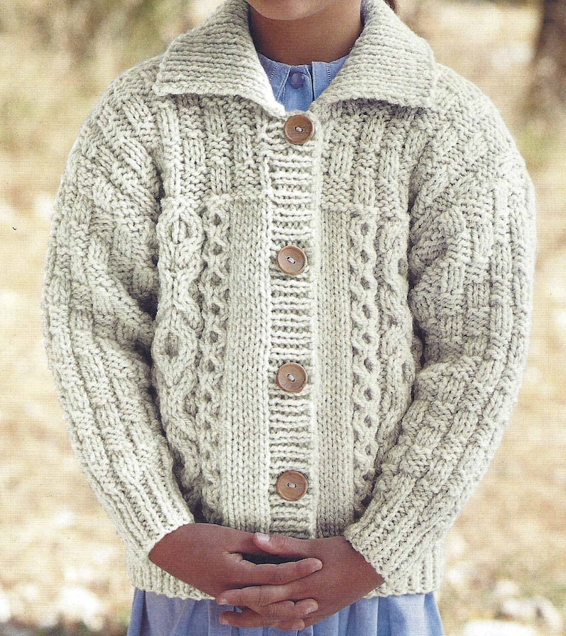 May include: A cream-colored knitted cardigan with a cable knit pattern and wooden buttons.