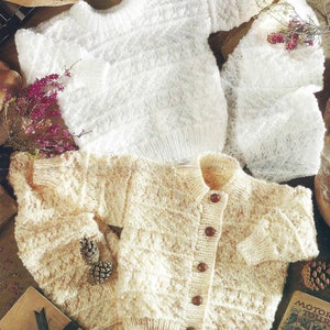 May include: Two knitted sweaters, one white and one cream, with a textured pattern. The cream sweater has buttons down the front.
