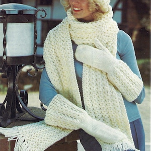 May include: Cream-colored knitted winter set including a hat, scarf, and mittens. The scarf has a fringed edge. The set is made of a textured knit pattern, offering a cozy and warm aesthetic. The hat is a close-fitting style.