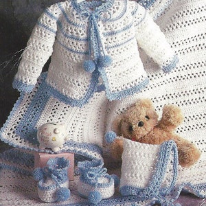 May include: A crocheted baby set in white and blue with a cardigan, booties, a hat, and a blanket. The set features blue trim and white pom-poms.