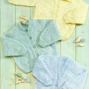 May include: Three knitted baby cardigans in different colours: yellow, light blue and green. Each cardigan has a button fastening and a speckled pattern.