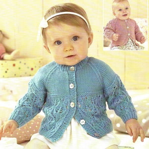 Puede incluir: Un cárdigan de punto azul claro para bebé con cierre de botones blancos y un delicado patrón de encaje. El cárdigan lo lleva puesto un bebé con una diadema blanca.