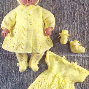 Puede incluir: Un conjunto de punto amarillo para muñeca con abrigo, vestido, polainas y botines. El conjunto está hecho con un delicado patrón de encaje.
