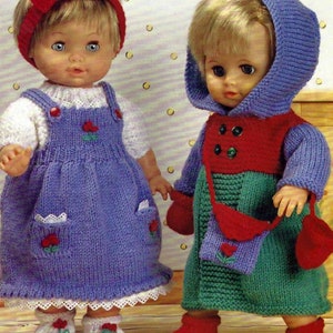 Puede incluir: Dos conjuntos de punto para muñecas, uno en morado y blanco con una diadema de lazo rojo, y el otro en verde, rojo y blanco con una chaqueta con capucha morada. Ambos conjuntos tienen detalles de flores.