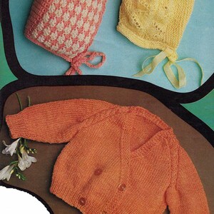 May include: A set of knitted baby clothes, including a pink and white checkered bonnet, a yellow crocheted bonnet, and a peach-colored cardigan with buttons.