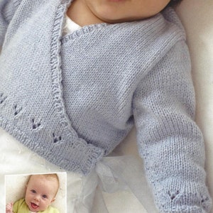 Op de afbeelding: Een lichtblauwe gebreide baby-cardigan met een wikkel-stijl en een delicaat kantpatroon. De cardigan is gebonden met een wit lint.