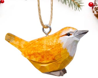 May include: A hand-carved wooden bird ornament featuring a vibrant yellow body with white accents on the chest and face. The bird has a dark grey beak and feet, and is suspended by a natural tan twine loop attached to a silver metal eye screw.