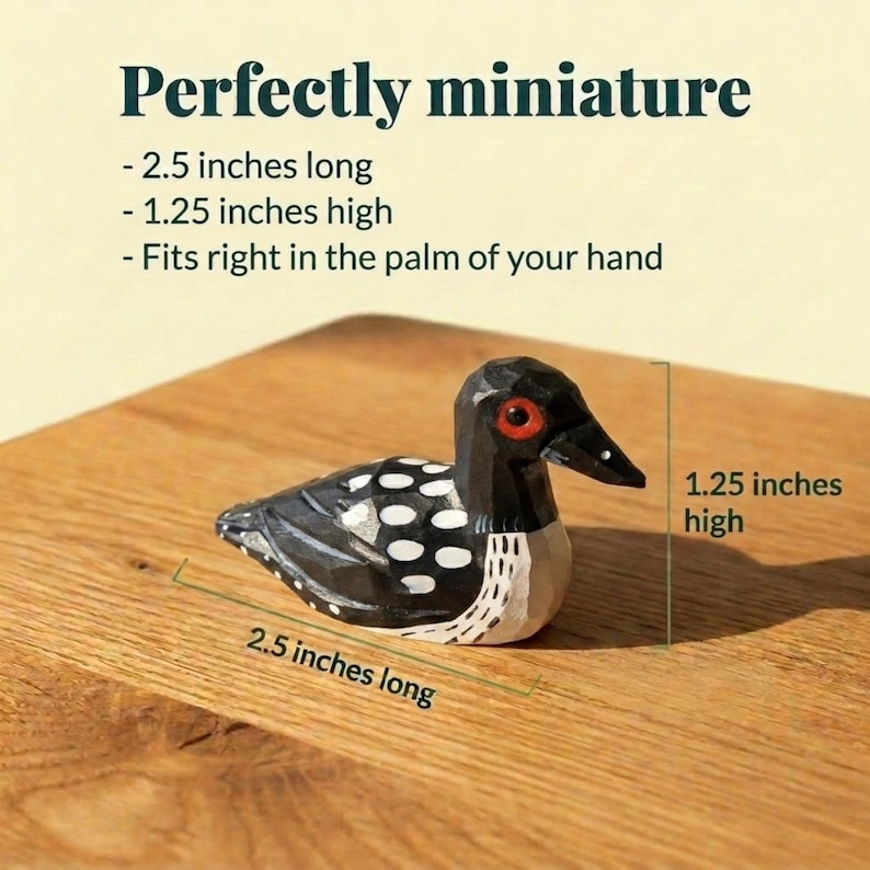 May include: A miniature carved wooden loon figurine with black, white, and red details. The text reads: Perfectly miniature, 2.5 inches long, 1.25 inches high, Fits right in the palm of your hand. Dimensions are marked as 2.5 inches long and 1.25 inches high.