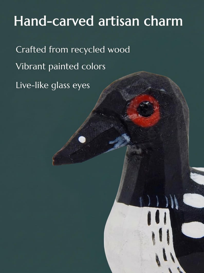 K&ouml;nnte beinhalten: Eine handgeschnitzte Vogelfigur aus Holz mit schwarzem Kopf, rotem Auge und wei&szlig;er Brust mit schwarzen Markierungen. Der Text lautet: Hand-carved artisan charm, Crafted from recycled wood, Vibrant painted colors, Live-like glass eyes.