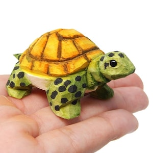 May include: Hand-carved wooden turtle figurine with a yellow shell and green spotted body.
