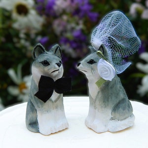 Könnte beinhalten: Eine graue und weiße Wolfsfigur mit schwarzer Fliege und eine graue und weiße Wolfsfigur mit weißem Schleier und weißer Blume.