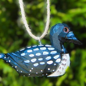 A wooden loon ornament with a blue and white painted design. The loon is hanging from a twine cord.