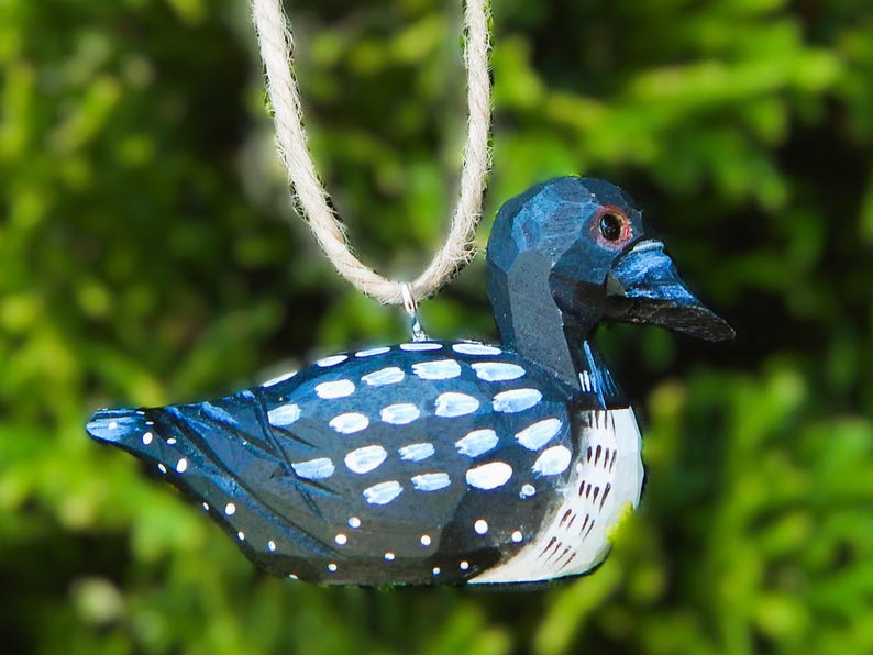 A wooden loon ornament with a blue and white painted design. The loon is hanging from a twine cord.