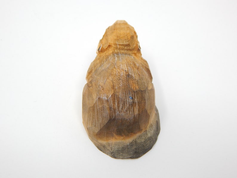 A wooden carving of a small animal, possibly a squirrel or a rabbit, with a light brown color and a rough, textured surface.