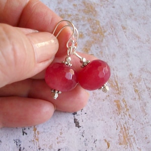 May include: A pair of silver earrings with pink gemstone beads. The beads are faceted and have a round shape.