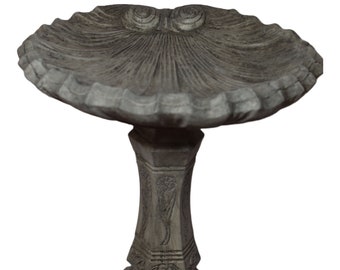 May include: A gray concrete bird bath with a scalloped edge and a decorative base. The base has a detailed design with a floral pattern.