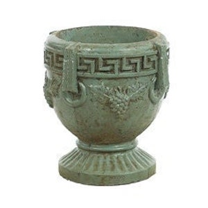 May include: A weathered, green-gray urn-shaped planter with a pedestal base. The planter features a Greek key design around the rim and decorative handles. Grape vine and leaf details are visible on the body of the planter.