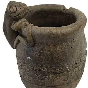 May include: A grey ceramic planter with a frog design. The planter has a wide opening and a rounded bottom. The frog is sculpted in a three-dimensional design and is positioned on the side of the planter.