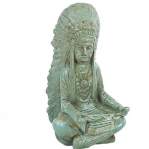 May include: A teal blue ceramic statue of a Native American man wearing a headdress and sitting in a meditative pose.