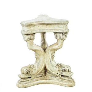 May include: A white, triangular table with a base sculpted in the shape of two dolphins. The table is made of a smooth, white material and has a slightly distressed finish.